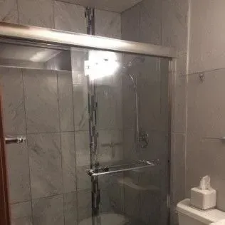 Shower with sliding glass doors; white tiled walls.