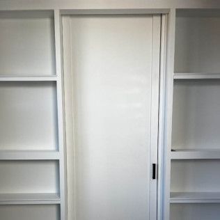 White door centered in built-in shelving with shelves on either side.
