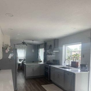 Kitchen with gray cabinets, white countertops, window, and appliances.