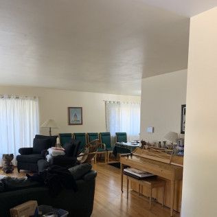 Living room with piano, seating, and table set for a meal.