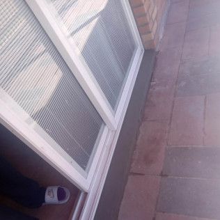 White-framed window next to brick wall and stone floor. A foot with a sneaker is visible.