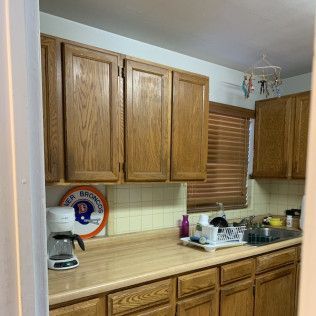 Kitchen interior with wooden cabinets, countertop, window, and appliances like a coffee maker.