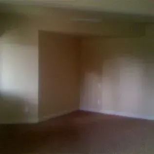 Empty room with light brown walls and dark brown carpet.