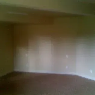 Empty room with beige walls and brown carpet.