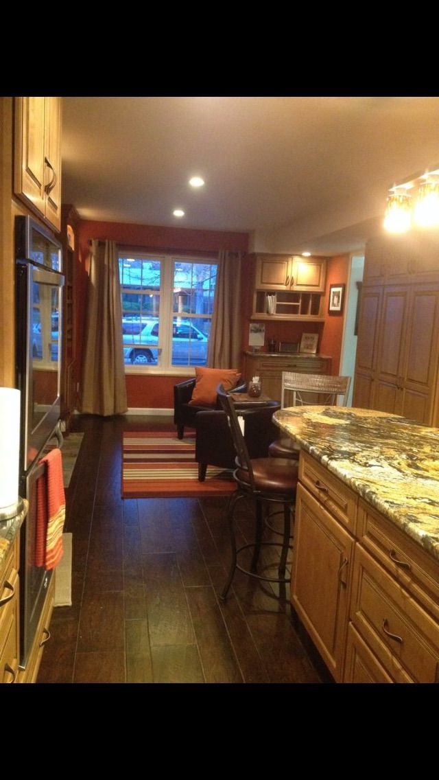 Living room with orange walls, hardwood floors, and a kitchen island with granite countertops.
