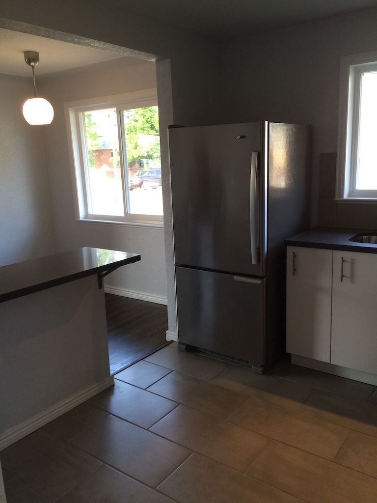 Kitchen with stainless steel refrigerator, white cabinets, and a dark countertop.