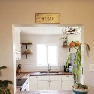 Kitchen interior with white cabinets, wooden countertops, and a “HOME” sign.
