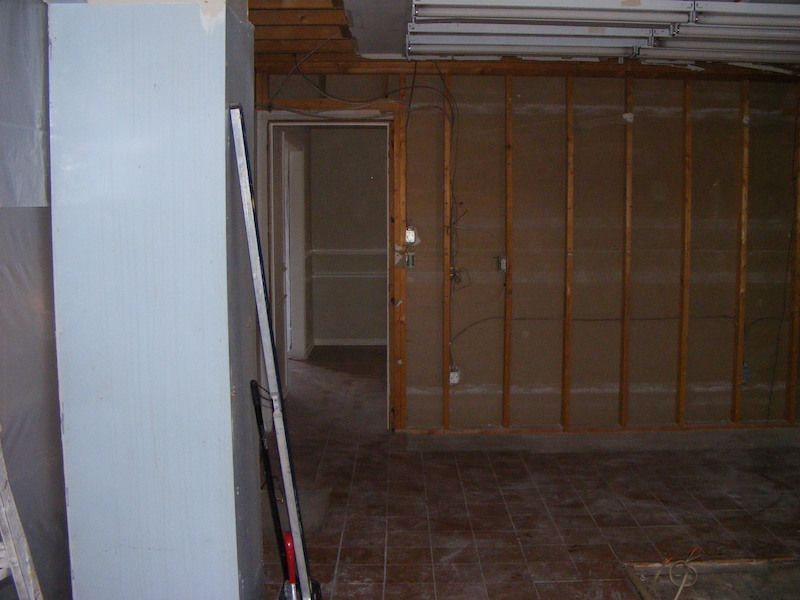 Interior under construction with exposed wall studs, doorway, and tile floor.