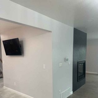 Interior view of a living space with a mounted TV, fireplace, and painted walls in gray and black.
