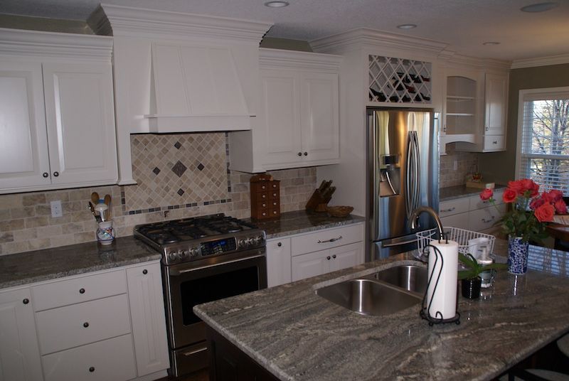 White kitchen with granite countertops, stainless steel appliances, and a wine rack.