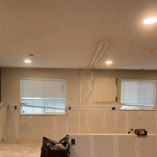 Basement under construction, drywall and window blinds. Recessed lighting.