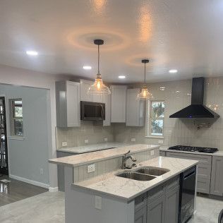 Modern kitchen with gray cabinets, quartz countertops, and stainless steel appliances.