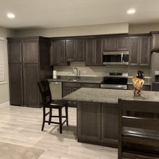 Kitchen with dark cabinets, stainless steel appliances, and a granite countertop island.