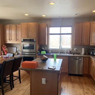 Kitchen with wood cabinets, stainless steel appliances, island, and window.