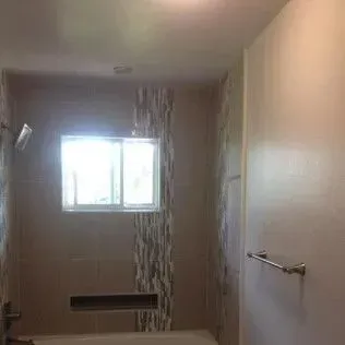 Bathroom with a window and tile backsplash. A towel bar is on the right.