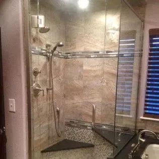 Glass shower enclosure with beige and mosaic tile, and a built-in bench.