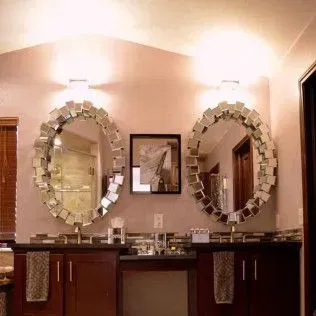 Two oval mirrors with square trim above a double sink vanity in a bathroom.