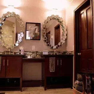 Bathroom with two vanities, oval mirrors, dark wood cabinets, and a framed picture.