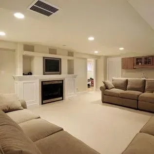 A beige living room with couches, a fireplace, and a TV.