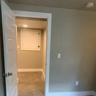 Doorway into a room with beige walls and a white access panel on the back wall.