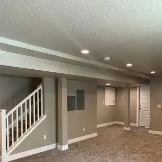 Basement interior with stairs, neutral walls, carpet, and recessed lighting.