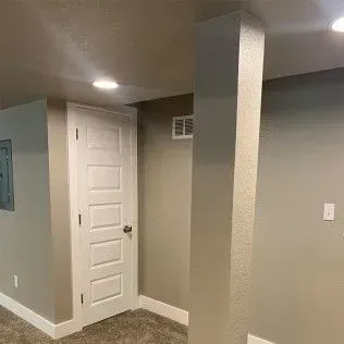 Interior room with a white door, beige walls, and a support column.