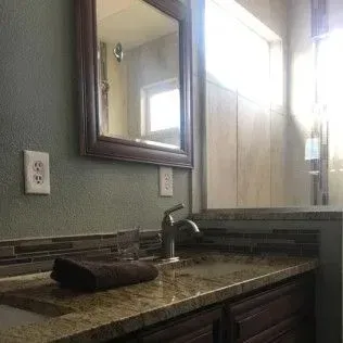 Bathroom with mirror, sink, and countertop. A brown towel rests on the countertop.