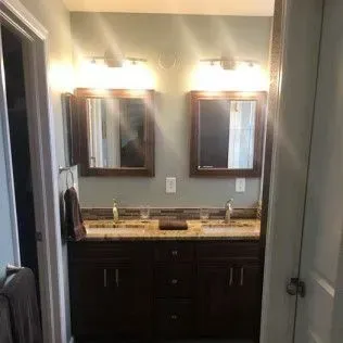 Bathroom with dual sinks, mirrors, and dark cabinets.