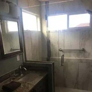 Bathroom with a shower, a vanity with a mirror, and a window.