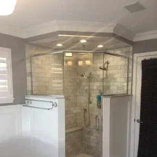 A spacious, modern shower with a glass enclosure, light-colored tile, and a built-in bench.