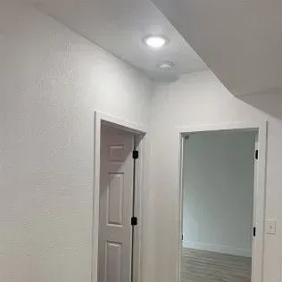 White hallway with two doors and recessed lighting.