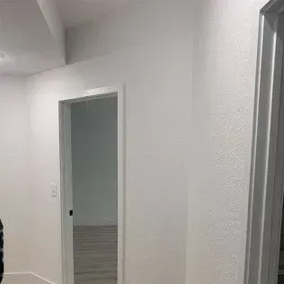 White hallway with doorway and textured wall.