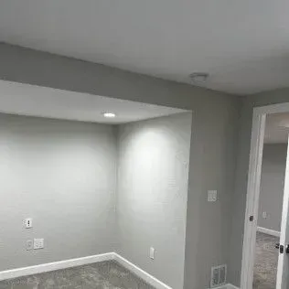 Gray room with an alcove and a doorway. Light-colored walls and carpet.