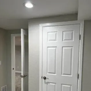 White doors in a room with a light fixture and an open doorway to another room.