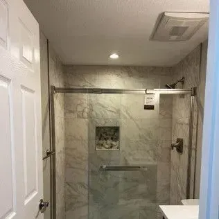 Bathroom with marble tiled shower, glass door, and stainless steel hardware.