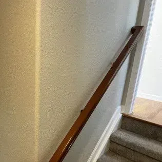 Wooden handrail on a staircase next to a wall.