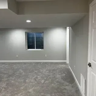 Empty room with gray carpet, walls, and a window with blinds.