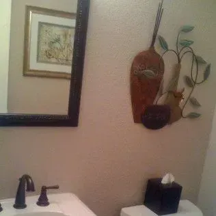Bathroom with a mirror, art on the wall, and a faucet and toilet.
