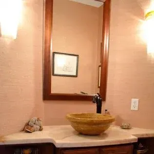 Bathroom with a brown framed mirror, a vessel sink, and beige walls.