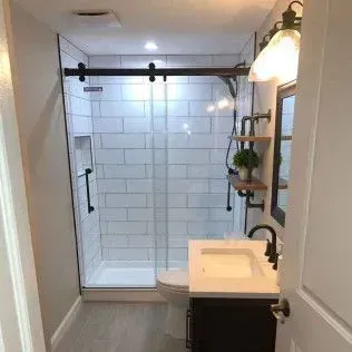 Bathroom remodel with a glass shower, subway tile, and black fixtures.