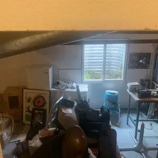 Cluttered basement with window, storage, and workbench.