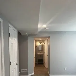 Interior hallway with white doors, light gray walls, and recessed lighting.
