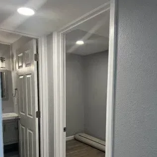 Hallway with doorway leading to a gray-painted room, another door to the left.