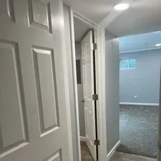 White doors open into a hallway and a room with gray walls and carpet.