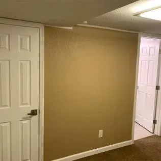 Interior room with tan walls, white trim, two white doors, and a light switch.