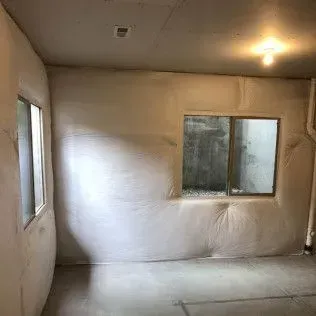 Basement interior with two windows. White insulation covers the walls, floor is concrete