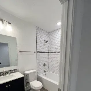 Bathroom with white brick tile shower and vanity with sink.
