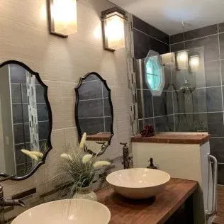 Bathroom with vessel sinks, ornate mirrors, sconces, and a walk-in shower.