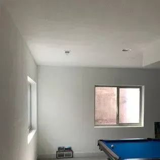 An empty game room with a pool table, a window, and white walls.