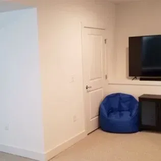 Blue beanbag chair in a white-walled room with a door and a TV on the wall.
